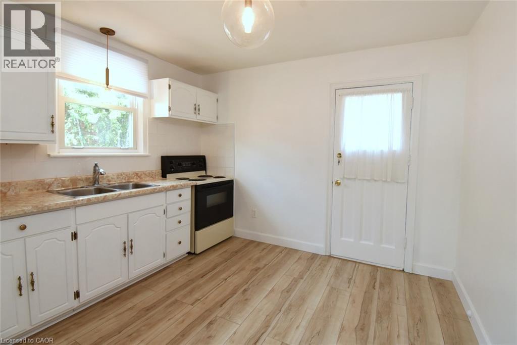 Kitchen featuring wood-finish flooring, white cabinetry, a double basin sink, and a built-in range - 575 Upper Wentworth Street, Hamilton, ON - Indoor Photo Showing Kitchen With Double Sink