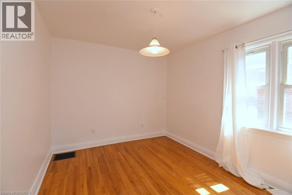 Hardwood flooring throughout, white painted walls, and a suspended ceiling light fixture - 575 Upper Wentworth Street, Hamilton, ON - Indoor Photo Showing Other Room