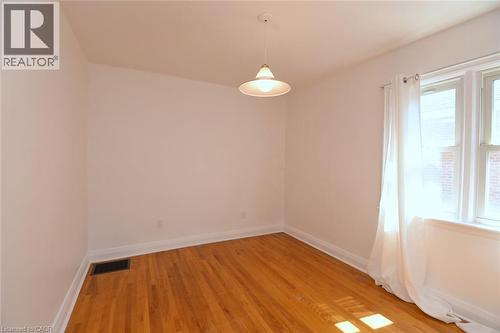 Hardwood flooring throughout, white painted walls, and a suspended ceiling light fixture - 575 Upper Wentworth Street, Hamilton, ON - Indoor Photo Showing Other Room