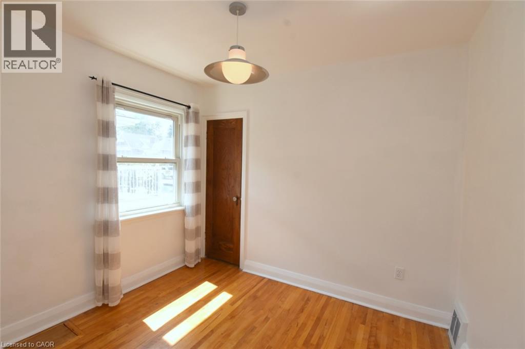 Hardwood flooring, painted walls, single-hung window, solid wood door, and a flush-mount light fixture - 575 Upper Wentworth Street, Hamilton, ON - Indoor Photo Showing Other Room