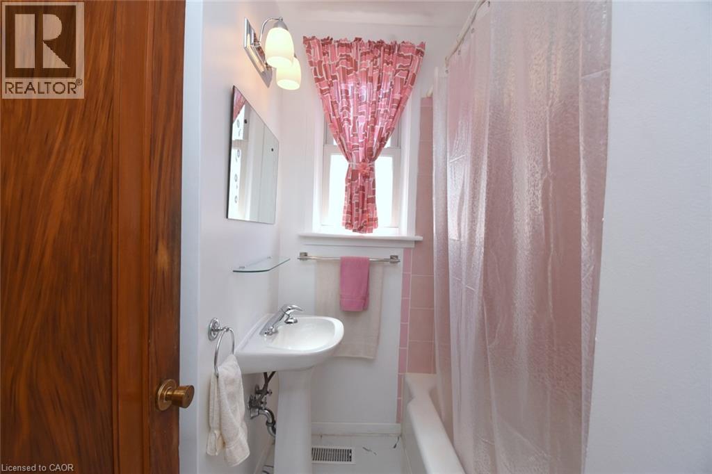 Pedestal sink with chrome faucet, wall-mounted light fixture, and window with trim - 575 Upper Wentworth Street, Hamilton, ON - Indoor Photo Showing Bathroom