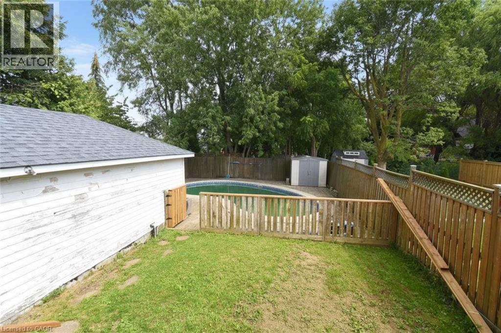 Fenced backyard featuring an inground swimming pool, a storage shed, and a detached building with an asphalt shingle roof - 575 Upper Wentworth Street, Hamilton, ON - Outdoor