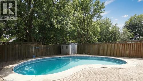 Curved swimming pool with tiled coping, brick paver surround, and wood privacy fencing - 575 Upper Wentworth Street, Hamilton, ON - Outdoor With In Ground Pool With Backyard