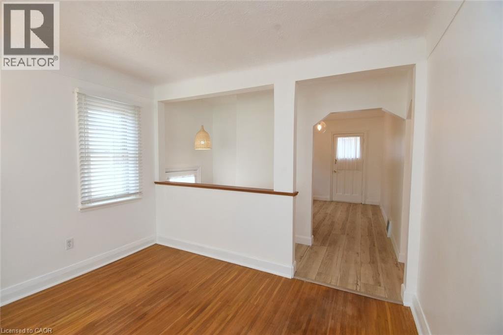 Bright open-concept living area featuring warm wood-finish flooring, white walls, and abundant natural light from a large window - 575 Upper Wentworth Street, Hamilton, ON - Indoor Photo Showing Other Room