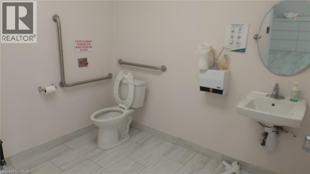 Ceramic tile flooring, wall-mounted sink, oval mirror, and grab bars - 64 Frederick Drive Unit# 101, Guelph, ON