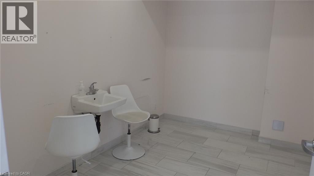 Wall-mounted sink with chrome faucet, light-toned wall finish, and tiled flooring - 64 Frederick Drive Unit# 101, Guelph, ON