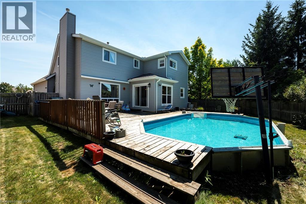 Expansive outdoor space featuring a pool with surrounding wood decking, a privacy fence, and mature trees - 364 Stoneheight Place, Waterloo, ON