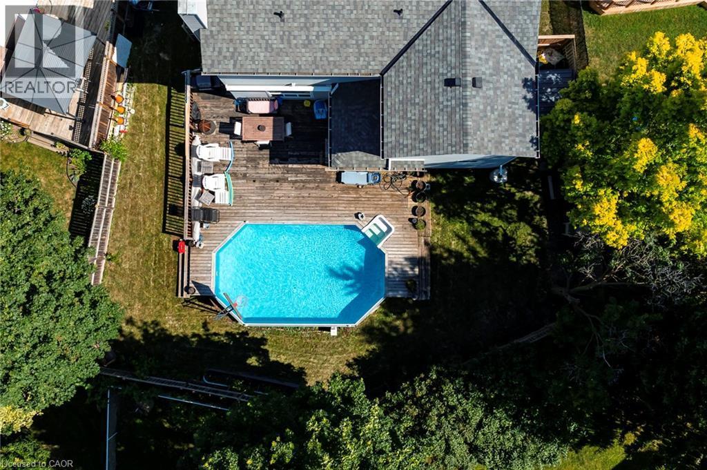 Wood-finish decking with an above-ground pool and surrounding green space - 364 Stoneheight Place, Waterloo, ON