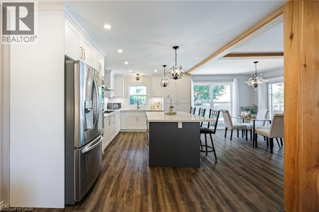 Kitchen featuring white cabinetry, stainless steel appliances, a dark-toned island with seating, and wood-finish flooring - 364 Stoneheight Place, Waterloo, ON