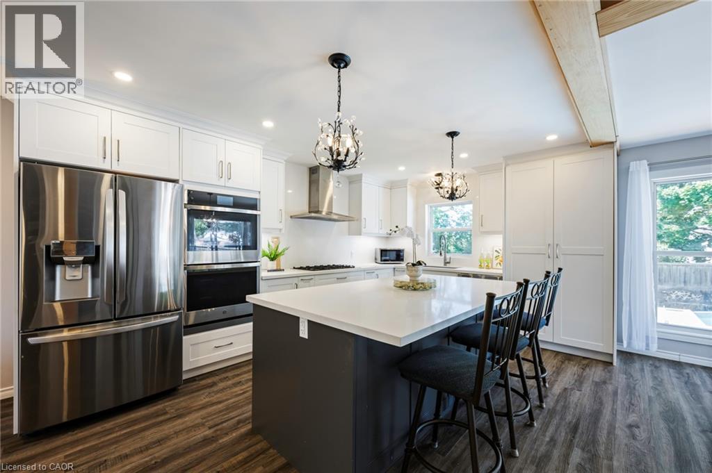 Stainless steel appliances, white cabinetry with crown molding, recessed lighting, wood-finish flooring, and a central island with a solid surface countertop - 364 Stoneheight Place, Waterloo, ON