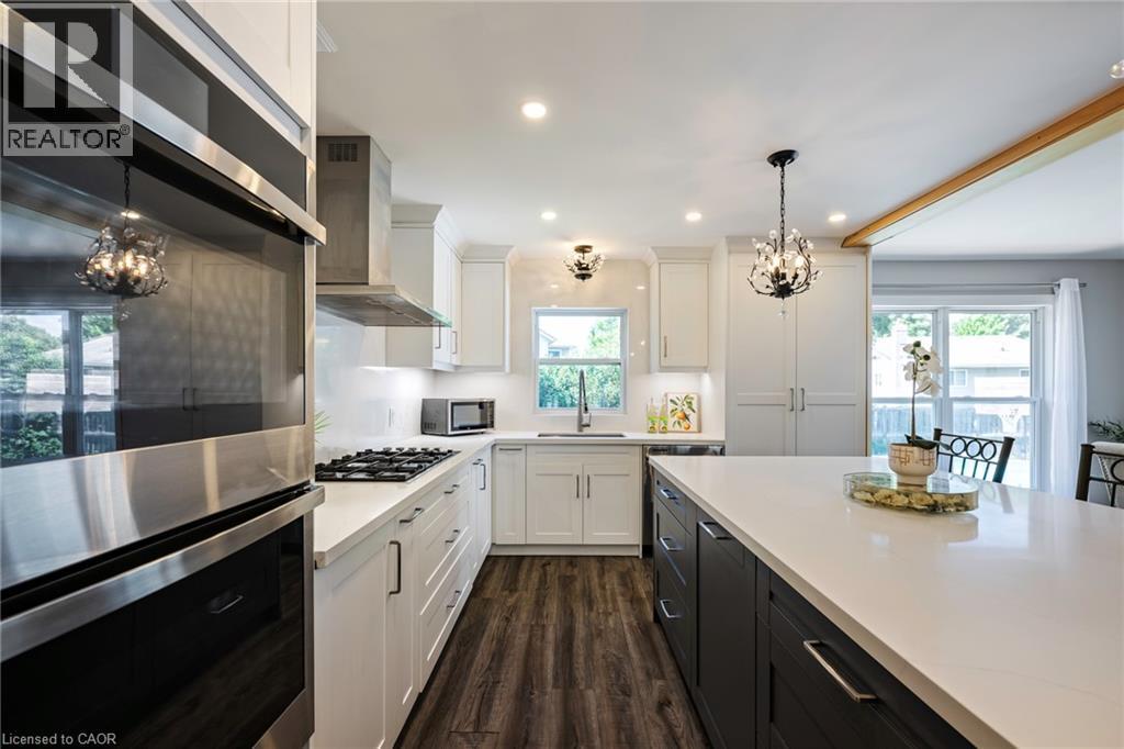 Gourmet kitchen featuring stainless steel appliances, wood-finish flooring, white cabinetry, a central island with white countertops, and recessed lighting - 364 Stoneheight Place, Waterloo, ON