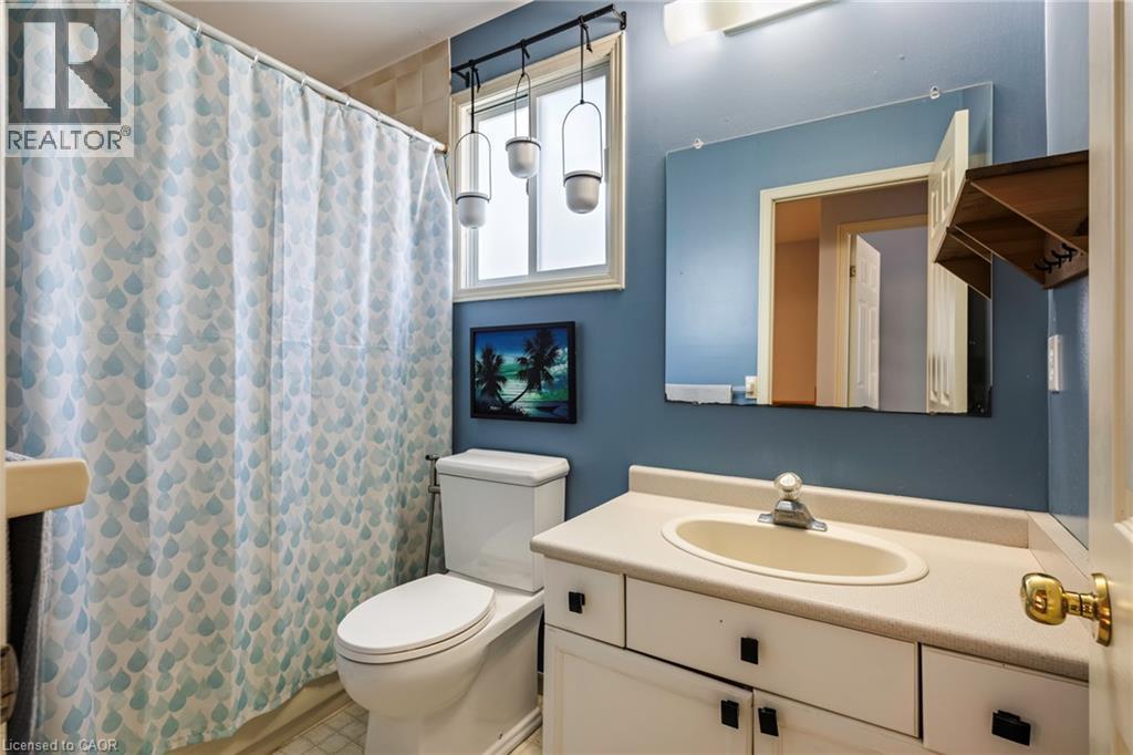 White vanity with integrated sink, chrome faucet, wall-mounted mirror, and overhead light fixture - 364 Stoneheight Place, Waterloo, ON