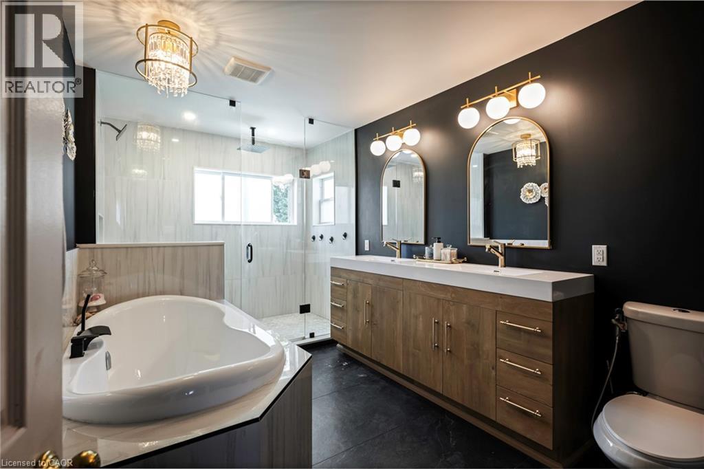 Dual vanity with gold-tone hardware, arched mirrors, and globe sconces - 364 Stoneheight Place, Waterloo, ON