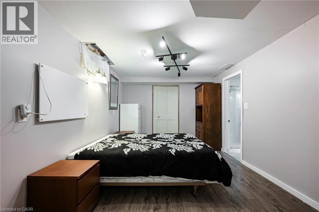 Wood-finish flooring, white walls, track lighting fixture, white paneled door, and a partially visible shower enclosure - 364 Stoneheight Place, Waterloo, ON