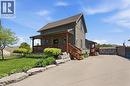 Two-story property featuring exterior siding, a covered front porch with exposed wood beams, and a stone foundation - 69 Nash Road S, Hamilton, ON 
