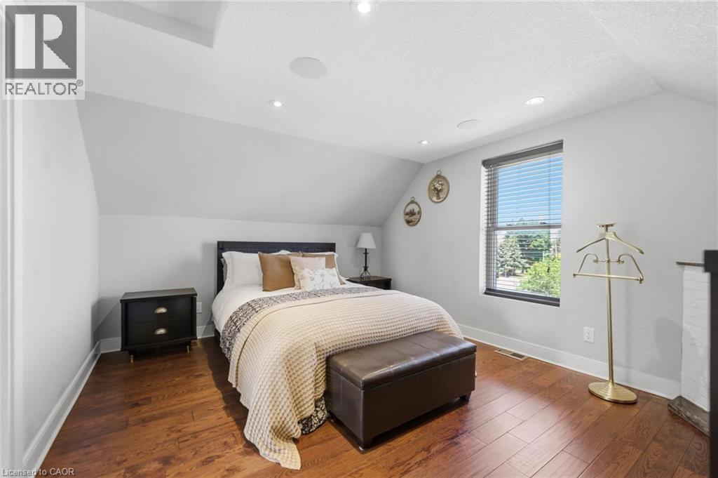 Bedroom featuring wood-finish flooring and a single window with horizontal blinds - 69 Nash Road S, Hamilton, ON