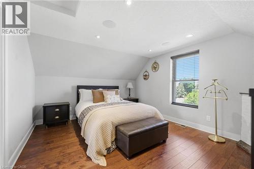 Bedroom featuring wood-finish flooring and a single window with horizontal blinds - 69 Nash Road S, Hamilton, ON 