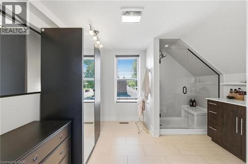 Light-toned tile flooring complements a spacious bathroom featuring a glass-enclosed shower with a built-in bench - 69 Nash Road S, Hamilton, ON 