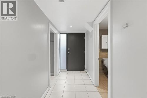Entryway featuring light-toned tile flooring, a modern dark-paneled door with an integrated frosted glass sidelight, and recessed ceiling lighting - 69 Nash Road S, Hamilton, ON 