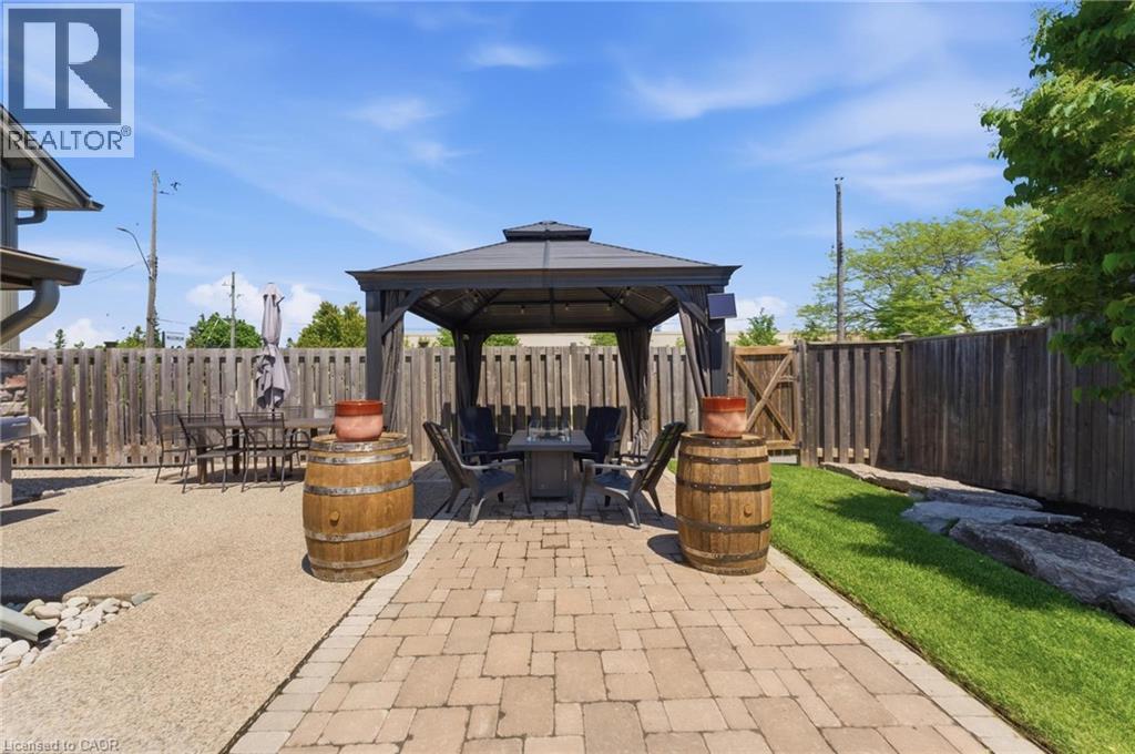 Outdoor entertaining area featuring a central gazebo with a hardtop roof and privacy curtains - 69 Nash Road S, Hamilton, ON
