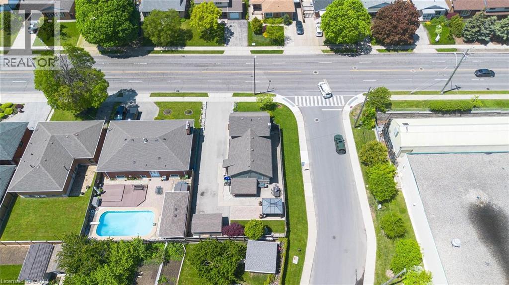 Expansive backyard featuring an in-ground swimming pool, a multi-level wood deck, and a paved patio area - 69 Nash Road S, Hamilton, ON