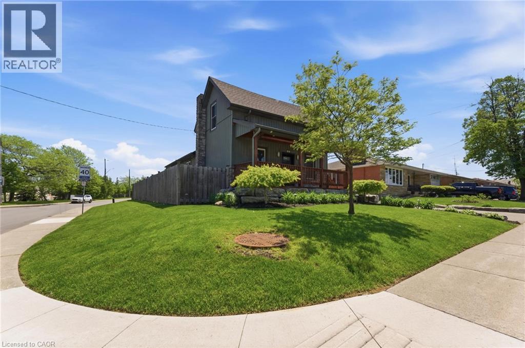 Corner property with a pitched roof, front porch, and mature landscaping - 69 Nash Road S, Hamilton, ON