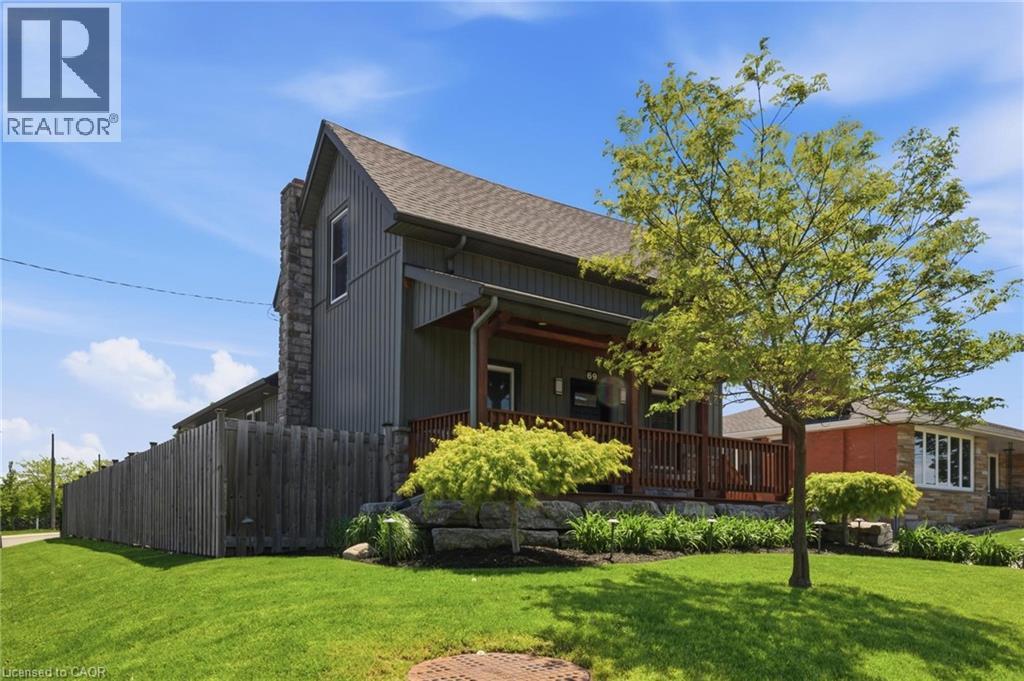 Exterior featuring dark vertical siding, a stone chimney, and a composite deck with wooden railings - 69 Nash Road S, Hamilton, ON