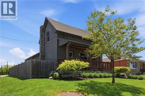 Exterior featuring dark vertical siding, a stone chimney, and a composite deck with wooden railings - 69 Nash Road S, Hamilton, ON 