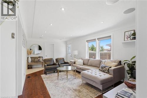 Bright living area featuring wood-finish flooring, recessed lighting, and large windows with white trim - 69 Nash Road S, Hamilton, ON 