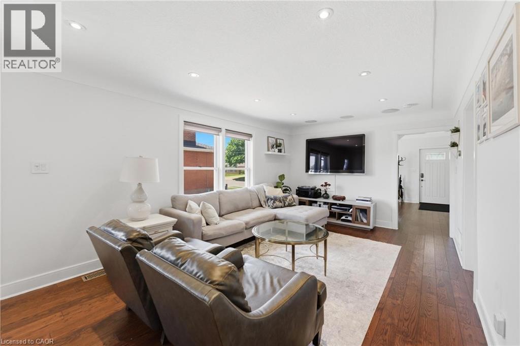Bright living area featuring wood-finish flooring, recessed lighting, and white baseboards - 69 Nash Road S, Hamilton, ON