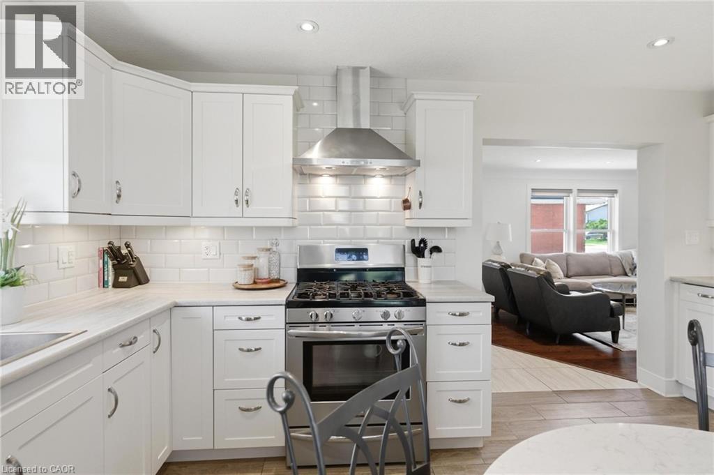 Kitchen featuring white shaker-style cabinetry, stainless steel appliances, a subway tile backsplash, and light-toned countertops - 69 Nash Road S, Hamilton, ON