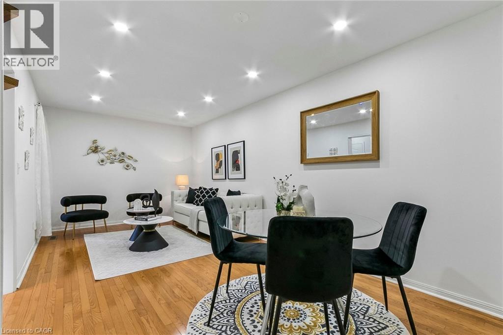 Wood-finish flooring throughout, recessed ceiling lighting, and a dining area featuring a round glass-top table - 1373 Quest Circle, Mississauga, ON
