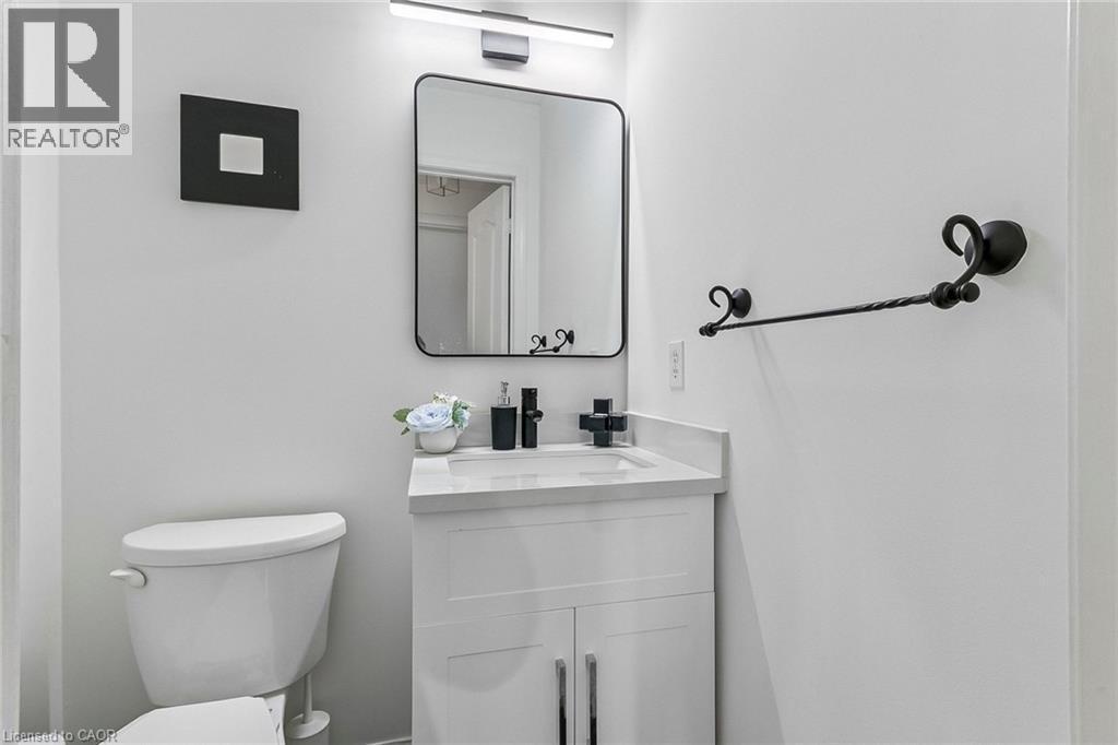 White vanity with a white countertop and integrated sink, black single-handle faucet, and a rectangular mirror with a black frame - 1373 Quest Circle, Mississauga, ON