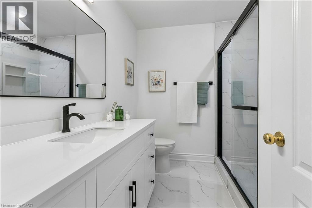 White vanity with integrated sink, black matte faucet, rectangular mirror, and a shower with black framed glass enclosure - 1373 Quest Circle, Mississauga, ON