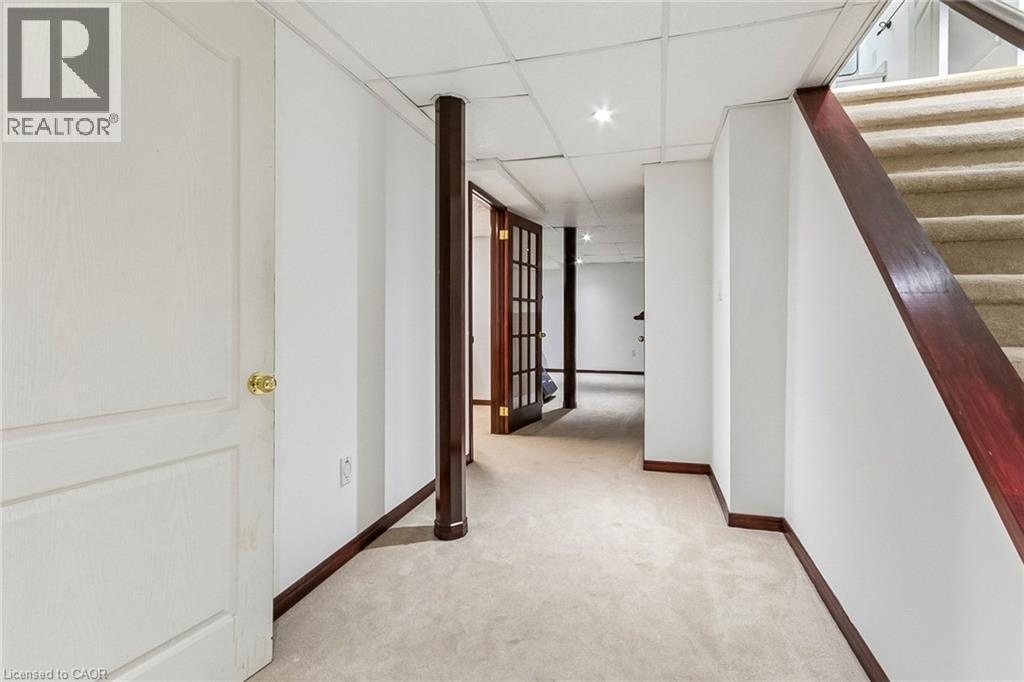 Carpeted flooring extending through a hallway with a drop ceiling, recessed lighting, and a white paneled door - 1373 Quest Circle, Mississauga, ON