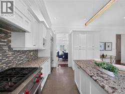 Gourmet kitchen with white cabinetry, stainless steel range, and stone countertops -
