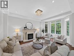 Living area featuring a detailed fireplace, a bay window with multiple panes, hardwood flooring, recessed lighting, and a prominent chandelier -