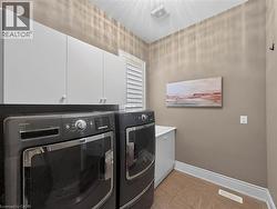White upper cabinetry, tiled flooring, integrated laundry sink with white vanity, and window with horizontal blinds -