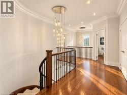 Hardwood flooring, curved staircase with wood banister and wrought iron spindles, modern tiered chandelier, recessed lighting, and crown molding -
