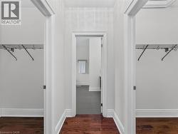 Hallway with wood-finish flooring, white trim, and two walk-in closets featuring wire shelving -