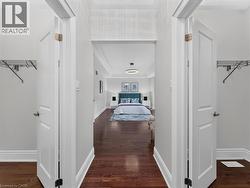 Hallway featuring wood-finish flooring, white panel doors, and crown molding -