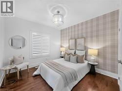 Hardwood flooring, window with white plantation shutters, textured plaid accent wall, white baseboards, and a crystal drum chandelier -