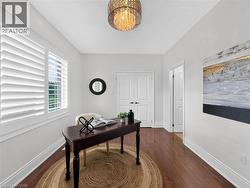 Wood-finish flooring, white plantation shutters, double panel doors, and a decorative ceiling light fixture -