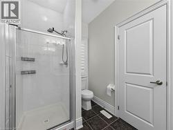 Glass-enclosed shower with white subway tile surround, dark tile flooring, white panel door, and window with plantation shutters -