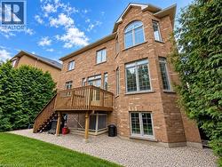 Brick exterior with multiple windows, elevated wooden deck with stairs, and a gravel-lined perimeter -