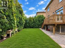 Expansive green lawn, mature perimeter hedges, and a raised wood deck with staircase access -