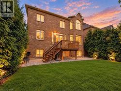 Brick exterior with multiple windows, featuring a wooden deck with stairs to the ground level -