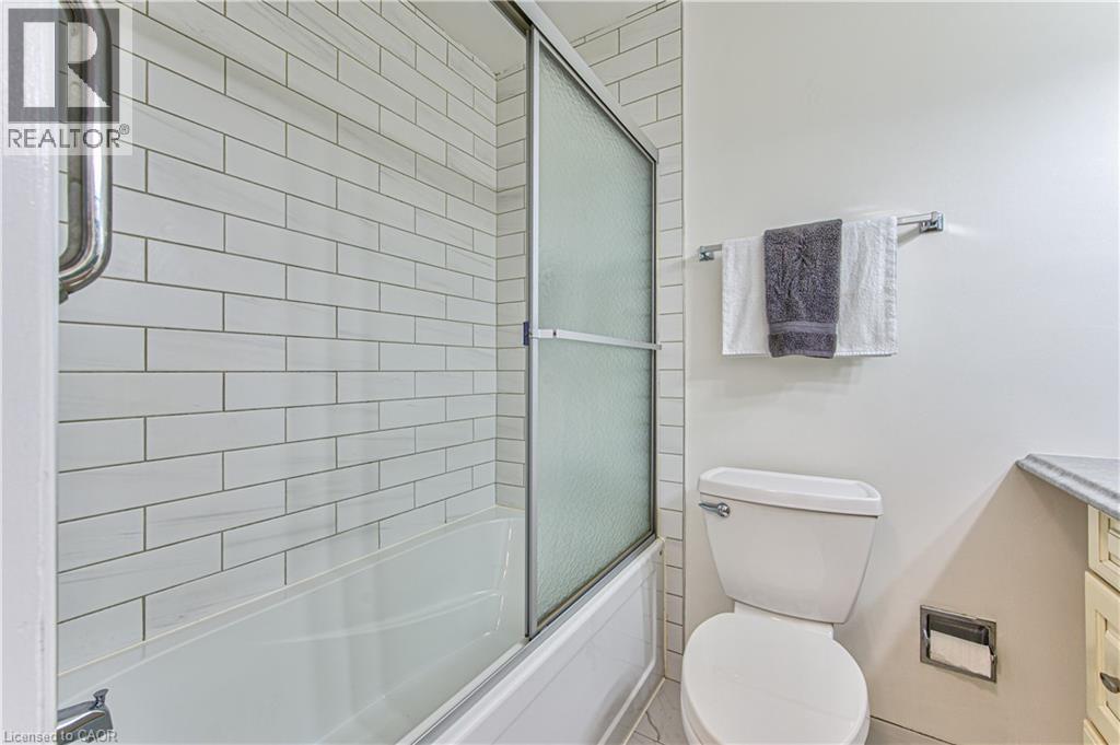 Main floor 4 pc bathroom with subway tiled tub to ceiling with glass doors. - 21 Vicmount Drive, Kitchener, ON