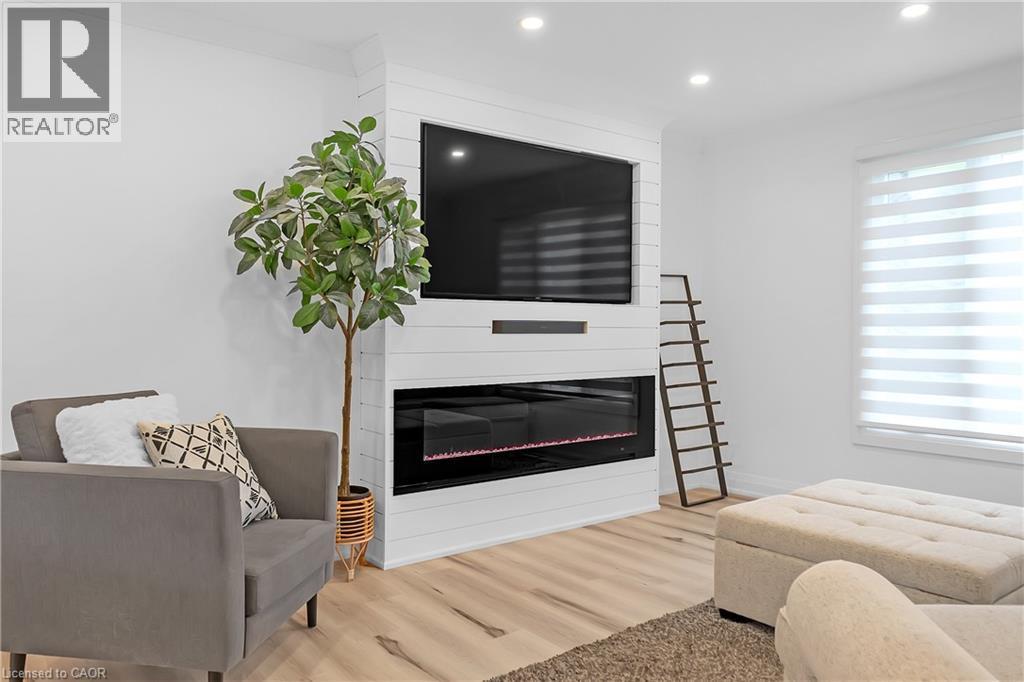 White shiplap-style media wall with an integrated linear electric fireplace - 4236 Longmoor Drive, Burlington, ON