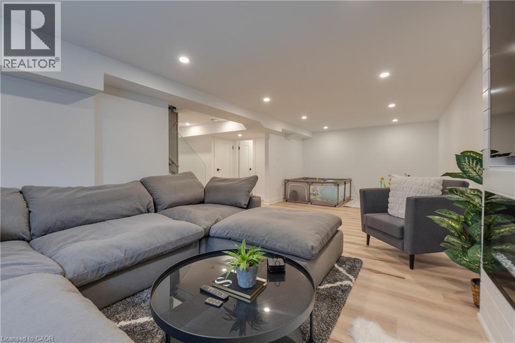 Recessed lighting, wood-finish flooring, white walls, and a visible staircase - 4236 Longmoor Drive, Burlington, ON
